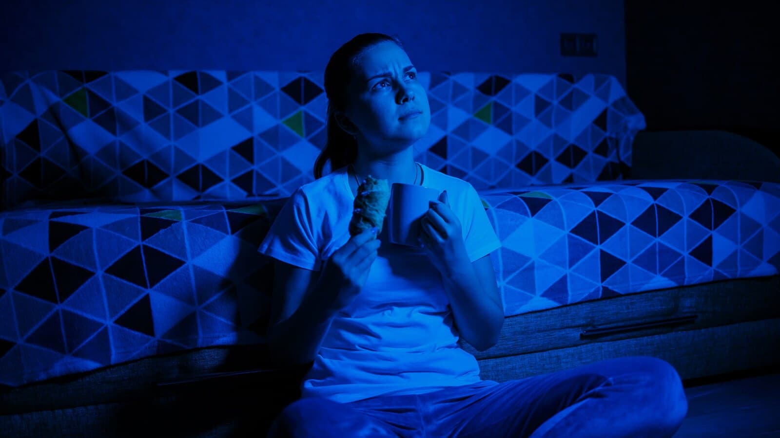 Person sitting on a couch after a scary movie with dim night lighting