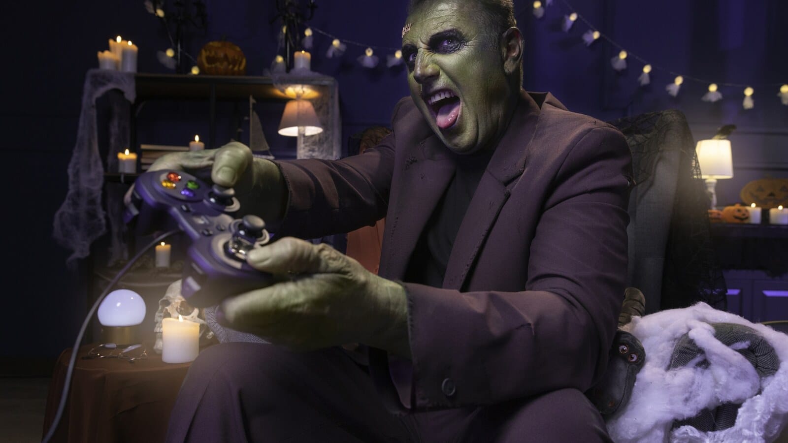 Gamer holding a controller while playing a scary game in a dark room